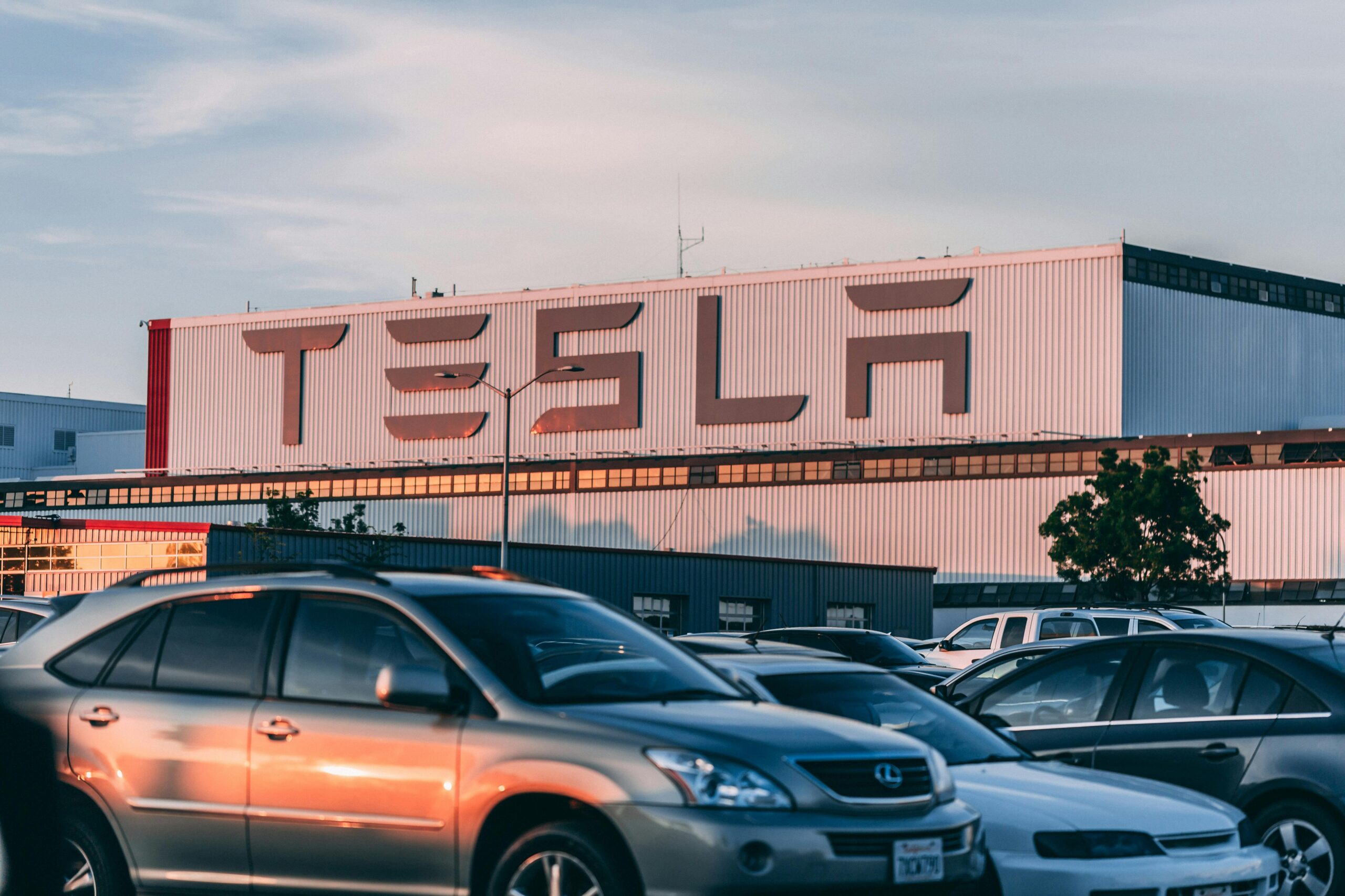 pexels-thatguycraig000-2449452 Tesla factory at sunset with the word TESLA prominently displayed against the setting sun